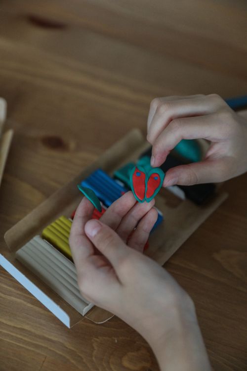 Hands shaping a colorful clay butterfly character